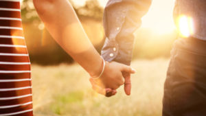 Young couple holding hands with sun-flare.